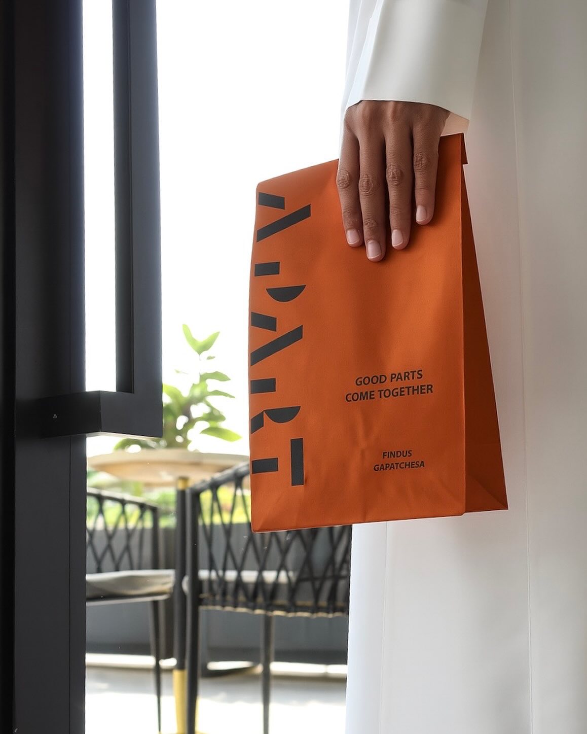 عميل ابارت يحمل كيس التوصيل البرتقالي — Apart Cafe branded delivery bag
